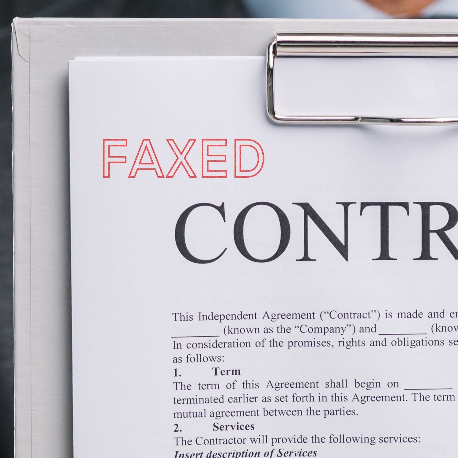 Close-up of a faxed independent agreement contract document with binder clip, highlighting legal terms and parties for business.