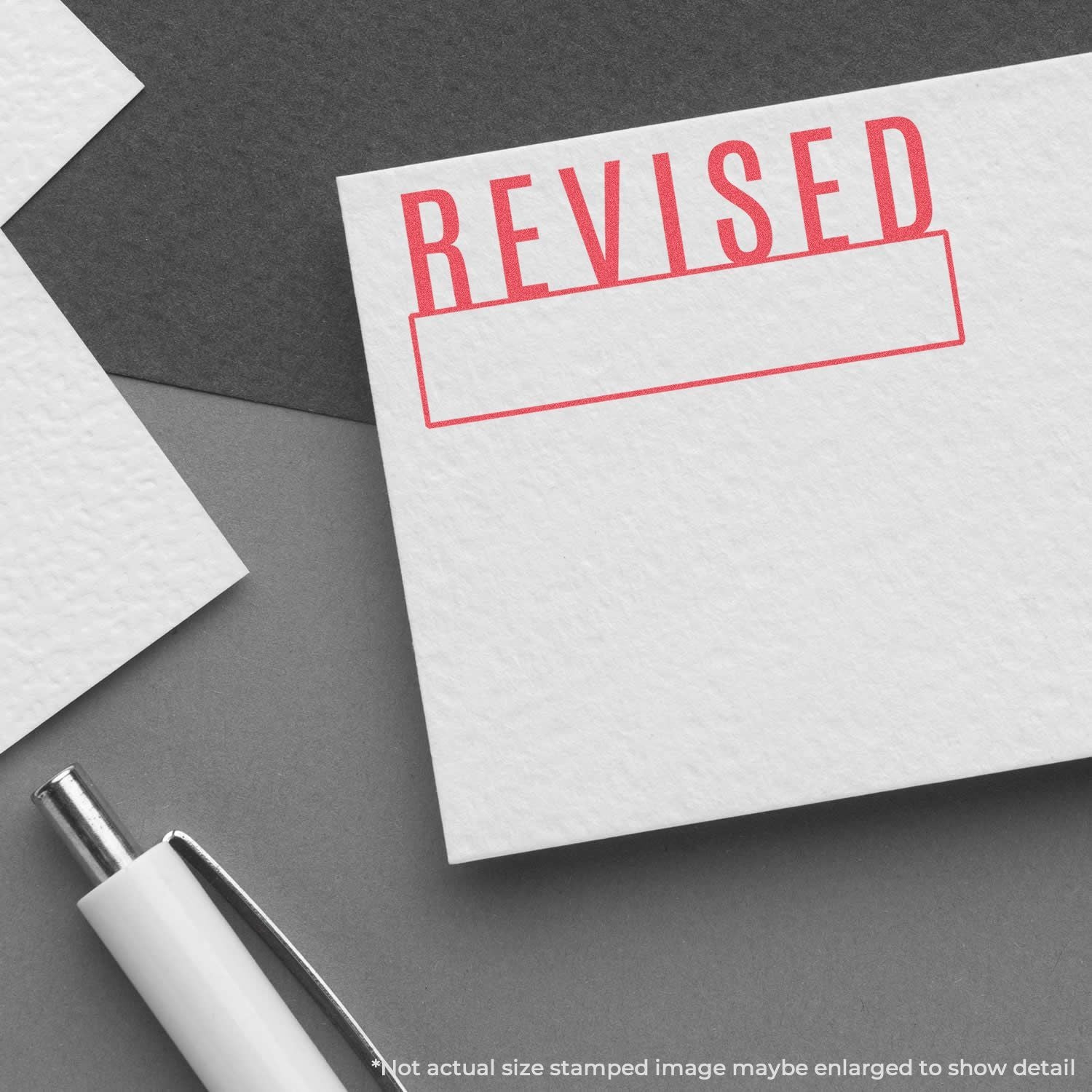 Revised stamp on document paper with pen on desk, representing updated changes for document editing and quality control workflow.